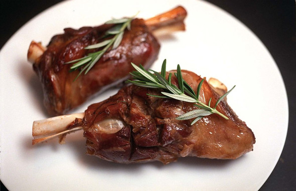 Lamb shanks with rosemary garnish.