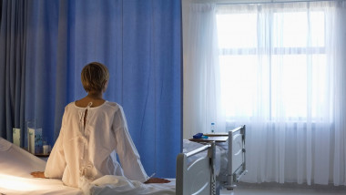 femeie cu spatele care sta pe marginea patului in spital