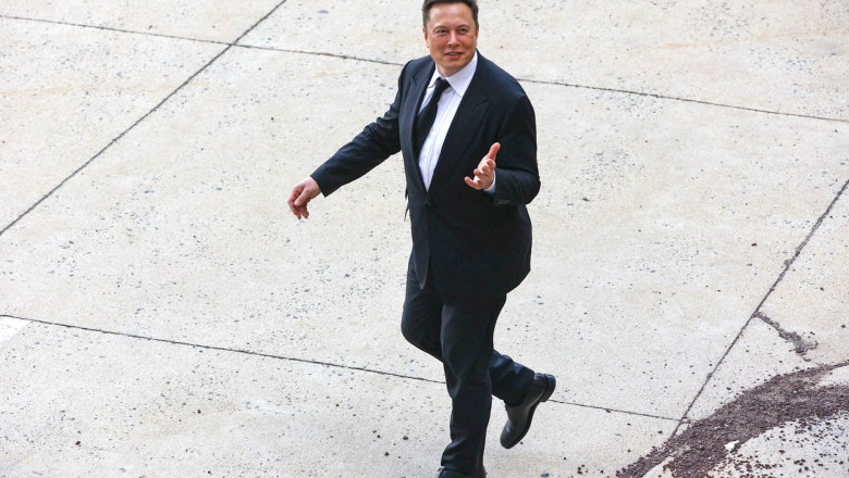 elon musk imbracat la costum merge si gesticuleaza