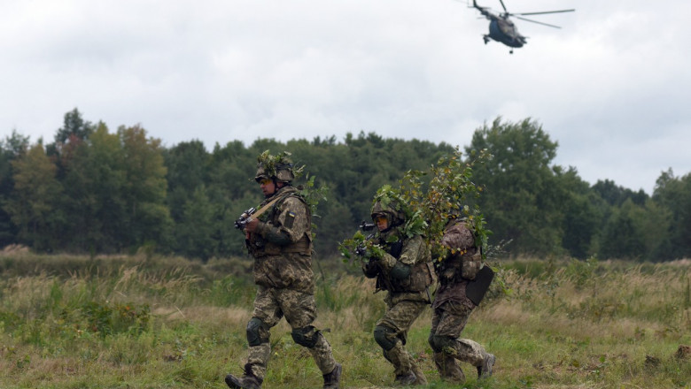 militari ucraineni cu un elicopter care zboară pe fundal