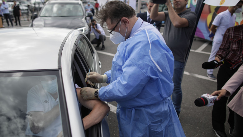 alexandru rafila in combinezon bleu cu masca vaccineaza pe cineva aflat in masina