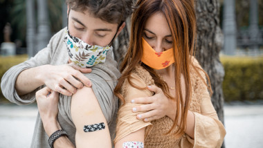 tineri cu masti care isi arata bratele dupa vaccin