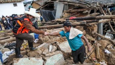 Peruvian President Pedro Castillo (L) helps a man next on the remains of a house destroyed by an earthquake in the department of Amazonas, northeast Peru
