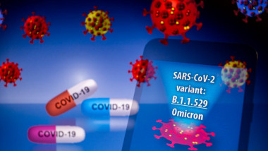 Illustration: In-camera multiple exposure image shows the words SARS-CoV-2 variant: B.1.1.529 Omicron on a smartphone in front of visual representation of virus and pills with word COVID-19 in its capsule