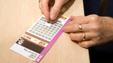 mainile unei femei în timp ce răzuie un bilet la loterie