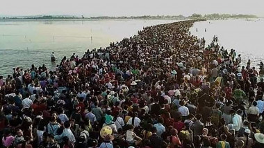 Mii de persoane care traversează un drum inundat în Myanmar.