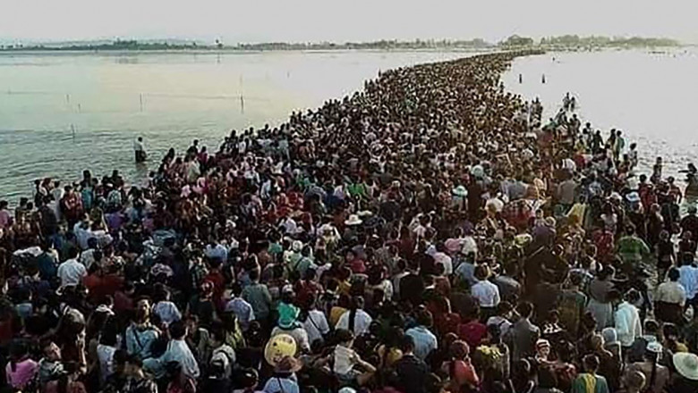 Mii de persoane care traversează un drum inundat în Myanmar.