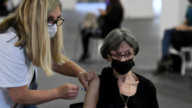 femeie cu masca intr-un centru de vaccinare, care se imunizeaza anticovid