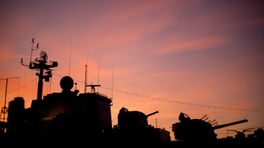 Silhouette of a retired warship against a firey red sunset.
