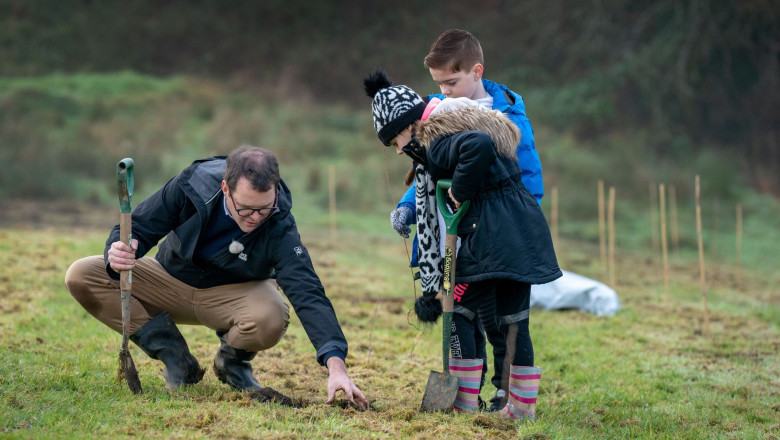 Ministrul adjunct pentru schimbări climatice, Lee Waters, din Țara galilor plantează stejari alături de doi copii.
