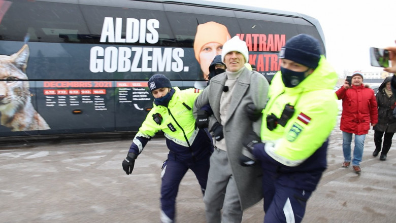 Deputatul leron Aldis Gobzems,in oardesiu si caciula, arestat de doi politisti in uniforma