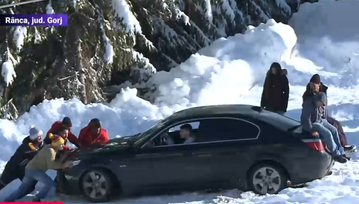 VIDEO. Zăpada le face deja probleme șoferilor la Rânca. Câțiva tineri s-au chinuit minute în șir să scoată un BMW dintr-o parcare