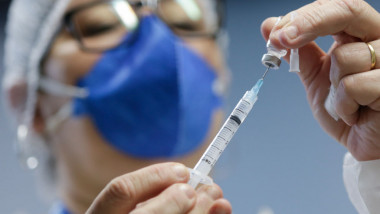 Un cadru medical pregătește o seringă pentru vaccin.