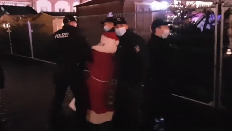 Polițiști germani rețin un Moș Crăciun fără mască.