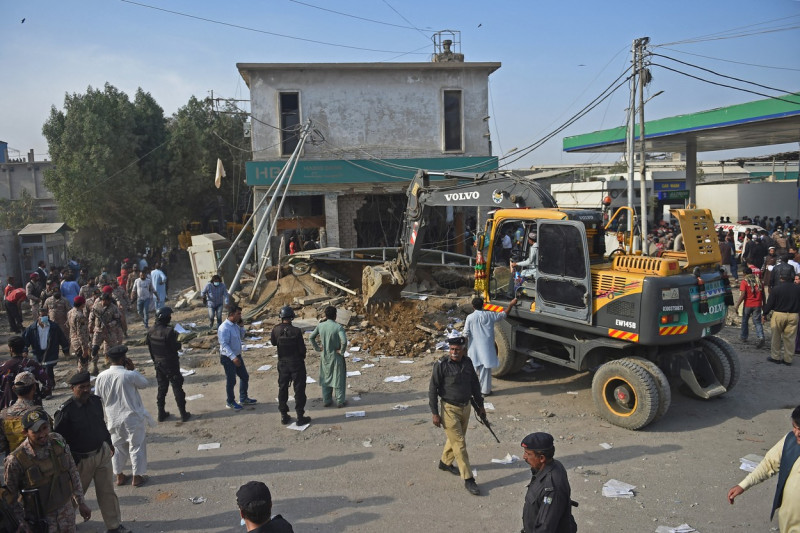 Excavator în apropierea unei clădiri care a fost distrusă de o explozie