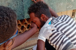 Un bărbat îi acoperă fața altuia din cauza gazelor lacrimogene la protestele din Sudan