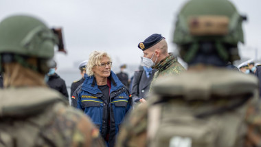 Christine Lambrecht, ministrul Apărării din Germania, in jacheta albastra, inconjurata de militari in uniforma