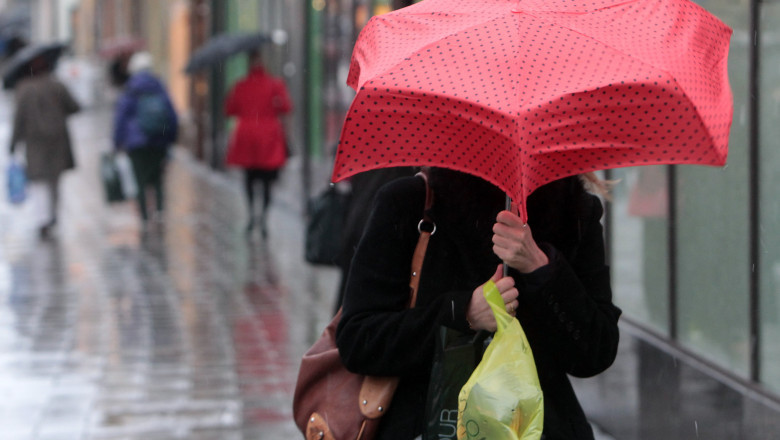 Oameni cu umbrele pe stradă, iarna.
