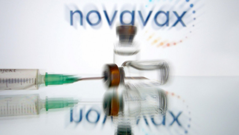 seringa si doze de vaccin pe fond usor neclar pe care scrie novavax