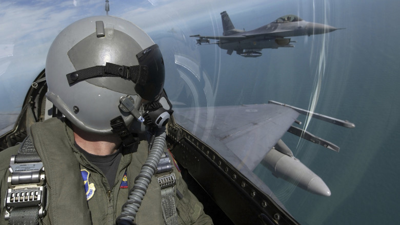 pilot care se uita in zbor cu capul intors la alte avioane F-16