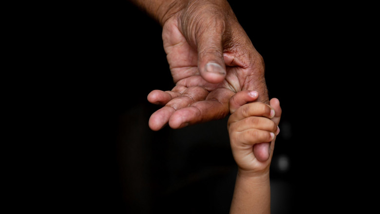 mana unui bebeluș care strânge degetul unei mâini de adult