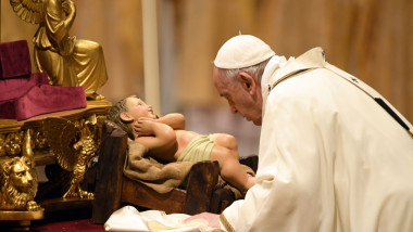 papa fracisc se apleaca asupra unei statuete a pruncului isus