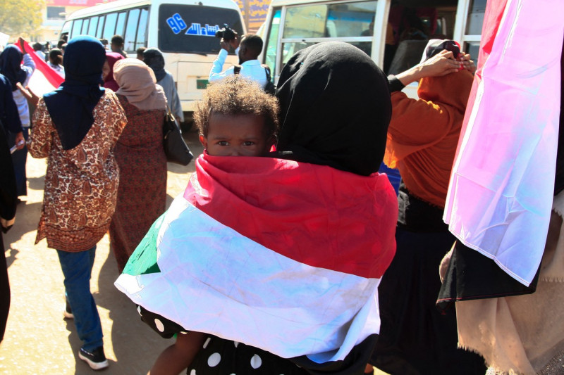 femei înfășurată într-un steag cu un copil în brațe