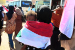 femei înfășurată într-un steag cu un copil în brațe
