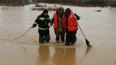 om salvat de pompieri cu capa pana la genunchi dupa inundatii