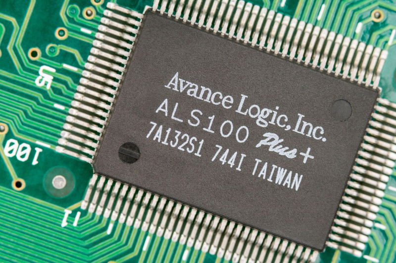 Macro close up shot of a microchip made in Taiwan on a audio sound card pcb with rows of pinouts visible. Chip made by Avance Logic.