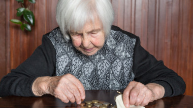 pensionara care numara monede pe o masa