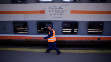 Angajat CFR, lângă un tren oprit la peron.