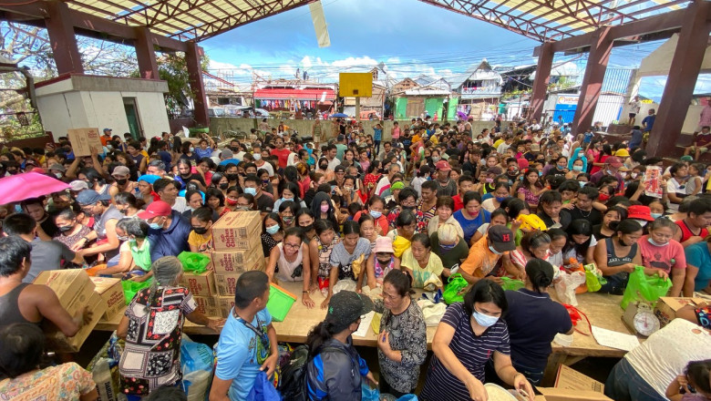 Oamenii afectați de taifunul din Filipine stau la coadă pentru a primi ajutoare.