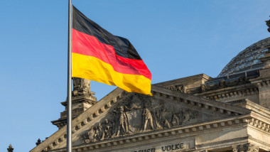 Drapel al Germaniei flutură în fața unei clădiri.