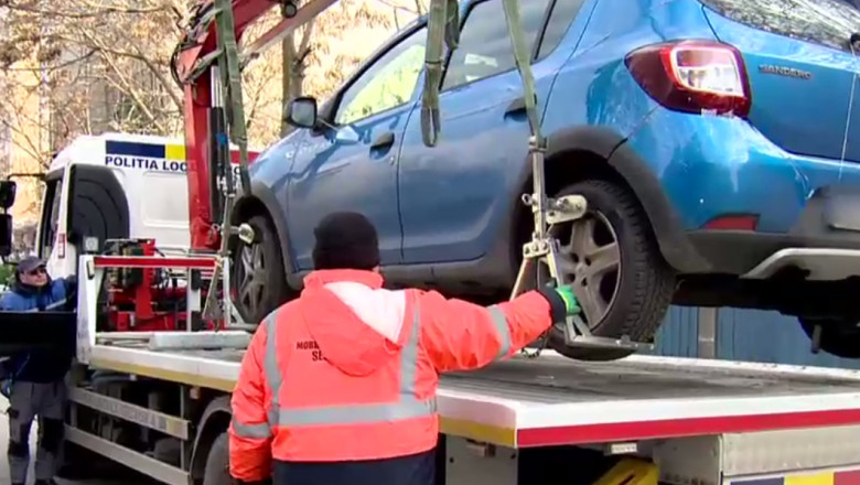 Autospecială care ridică o mașină parcată neregulamentar.