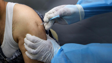 Un bărbat este vaccinat anti-COVID de un cadru medical.