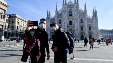 oameni cu masti care isi fac selfie in piata duomo din milano