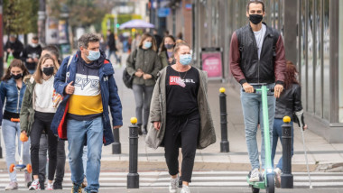 Oameni pe stradă, cu mască, în București.