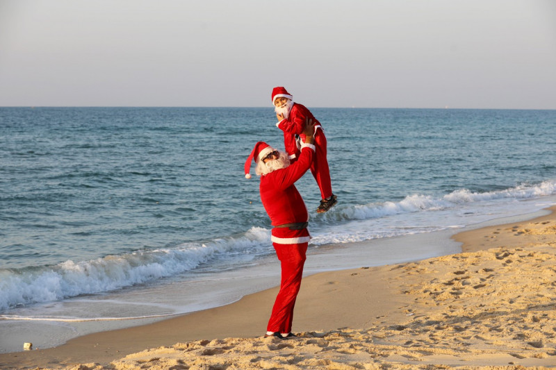 A Palestinian Christian man and his son dressed as Santa Claus walk along beach of in Beit Lahia sea in the northern of Gaza strip, Beit Lahia, Gaza Strip, Palestinian Territory - 27 Dec 2021