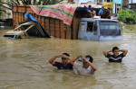 Oameni merg prin apă la inundațiile din Indonezia