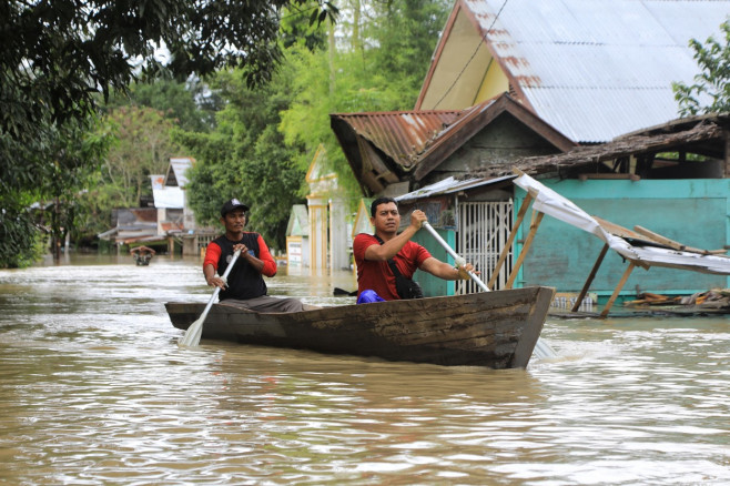 Oameni pe o barcă într-un oraș din Indonezia în timpul inundațiilor din 2022