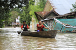 Oameni pe o barcă într-un oraș din Indonezia în timpul inundațiilor din 2022