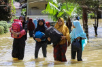 Oameni merg prin apă la inundațiile din Indonezia