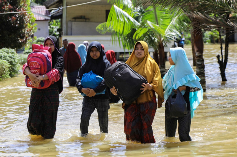 Oameni merg prin apă la inundațiile din Indonezia