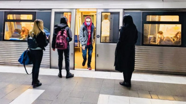 tanar cu masca coboara din metrou, alte fete asteapta sa urce