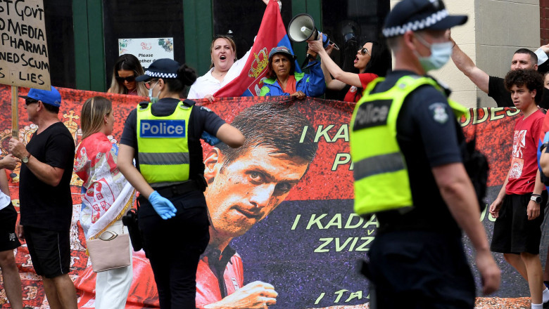 People hold placards up at a government detention centre where Serbia's tennis champion Novak Djokovic is reported to be staying in Melbourne on January 7, 2022