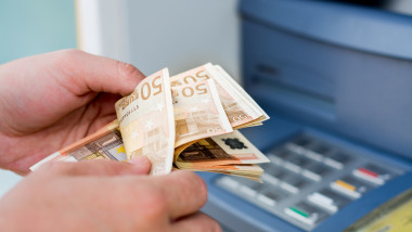 barbat care numara bancnote de 50 de euro scoase din bancomat