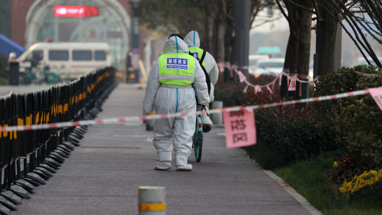 oameni cu combinezoane care dezinfecteaza strada in china