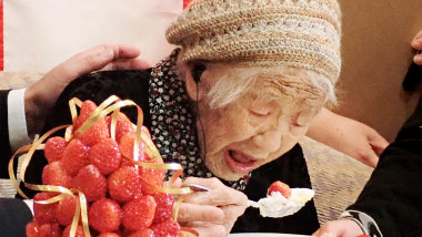 Femeie bătrână care mănâncă o prăjitură cu căpșune