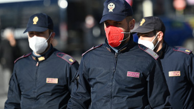 trei bărbati imbracati in uniformă de polițisti, unul dintre ei poarta masca de protectie de culoare roz